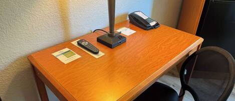 A wooden desk with a lamp, a telephone, and a notepad.