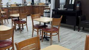 Un restaurante con mesas y sillas de madera, una máquina de café y un dispensador de agua.
