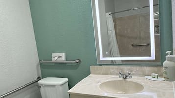 A bathroom with a toilet, sink, and mirror.