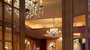 A grand ballroom with ornate chandeliers, elegant draped tables, and a luxurious carpet. - Hilton Rosemont Chicago O'Hare (Rosemont)
