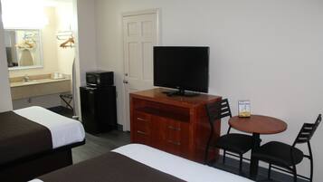 Een hotelkamer met twee bedden, een televisie, een bureau met stoel, en een kleine tafel met twee stoelen.