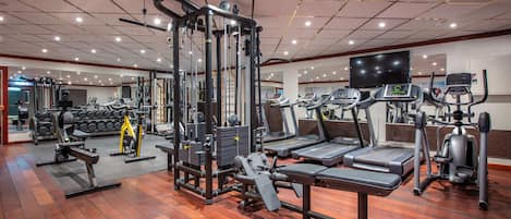 Une salle de sport équipée de divers appareils d’exercice, notamment des tapis de course, des appareils de musculation et des poids libres.