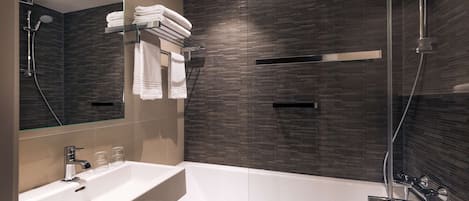 A modern bathroom with a glass-enclosed shower, a white sink, and neatly stacked towels.