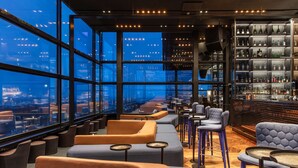 Zona de bar moderna con asientos y una amplia estantería para vinos.