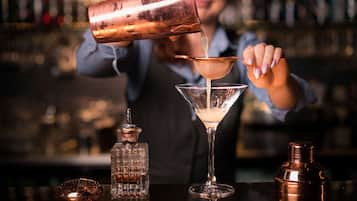 A bartender pouring a drink into a martini glass.
