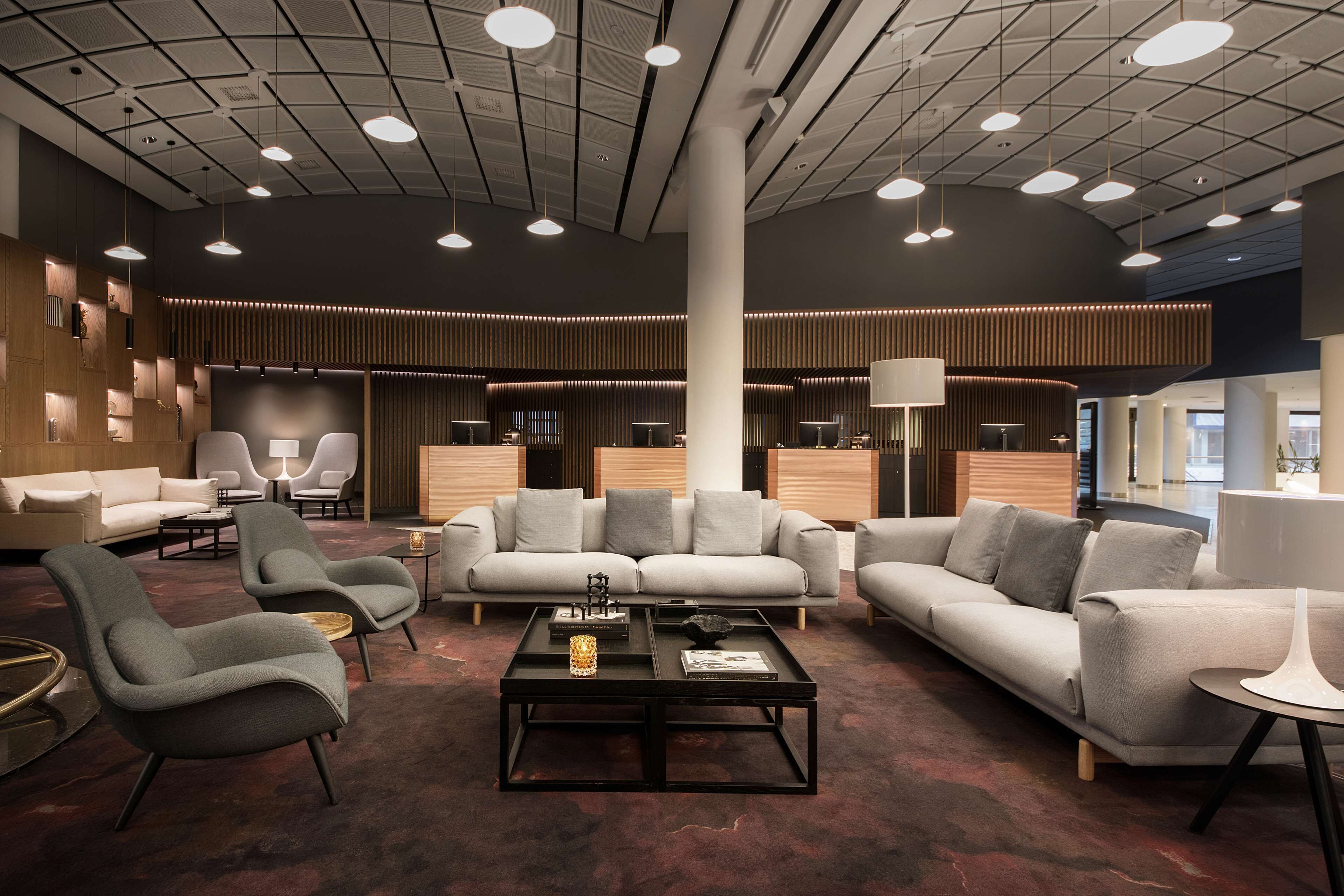 A modern lobby with sofas, armchairs, and a coffee table.