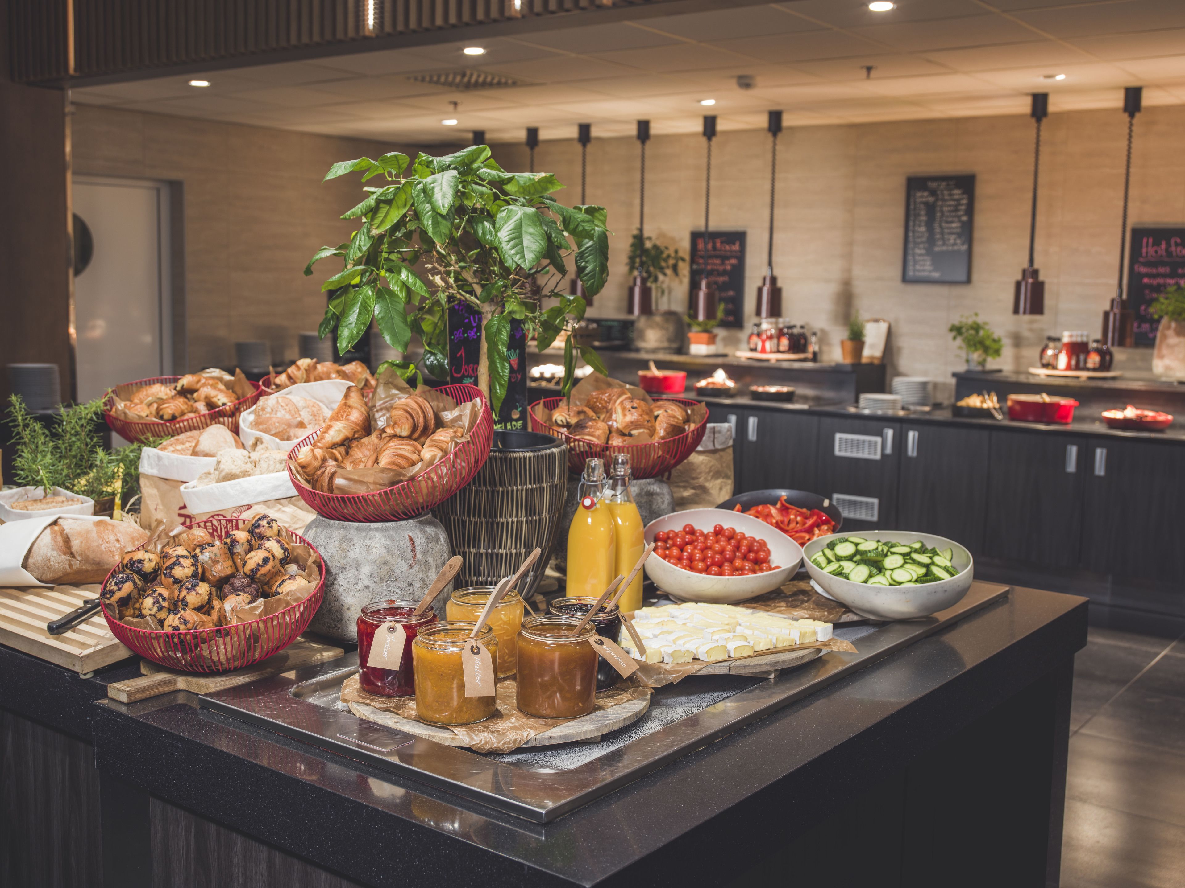 A buffet with various food items, including pastries, fruits, and condiments.