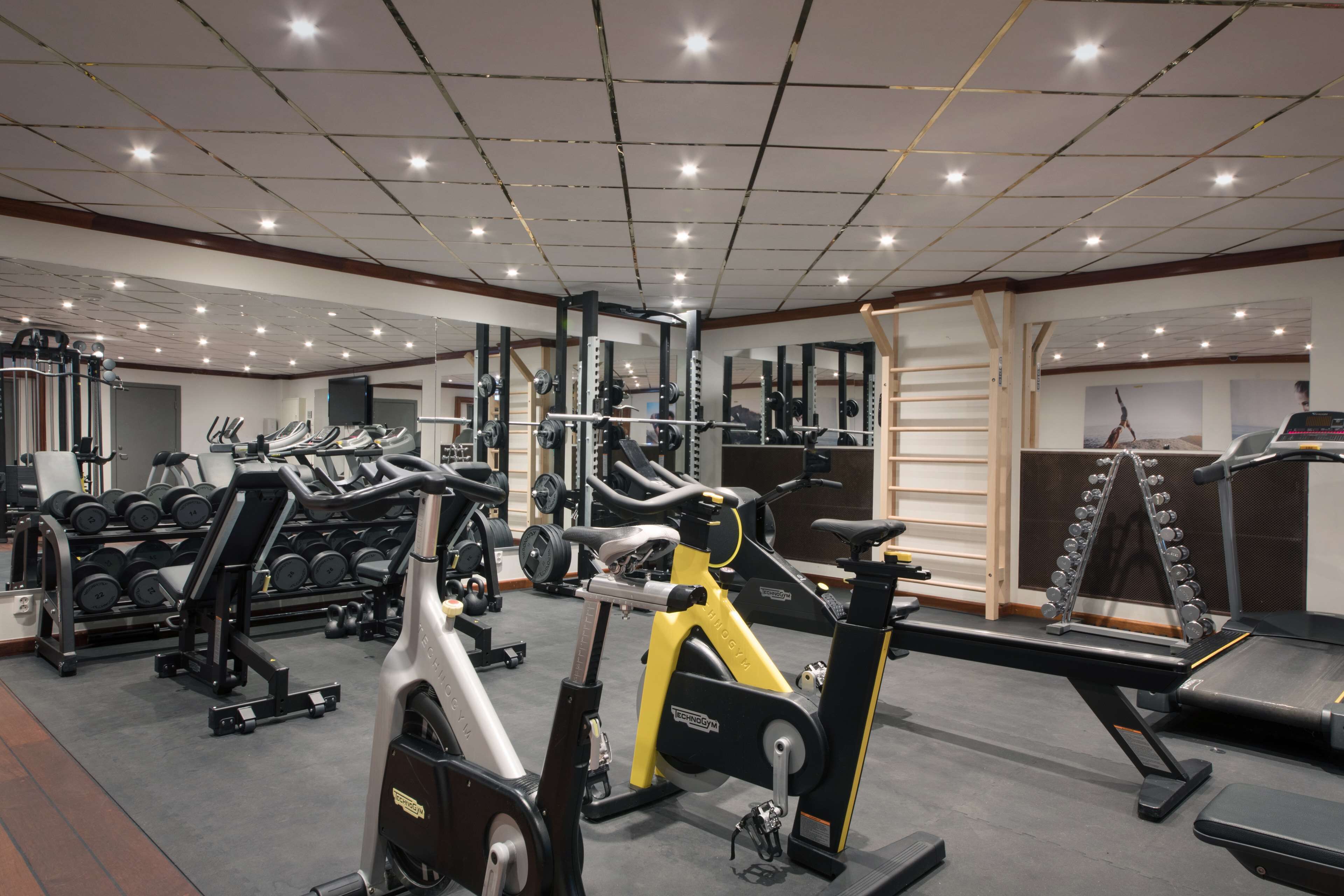 A gym with various exercise equipment, including treadmills, stationary bikes, and weight machines.