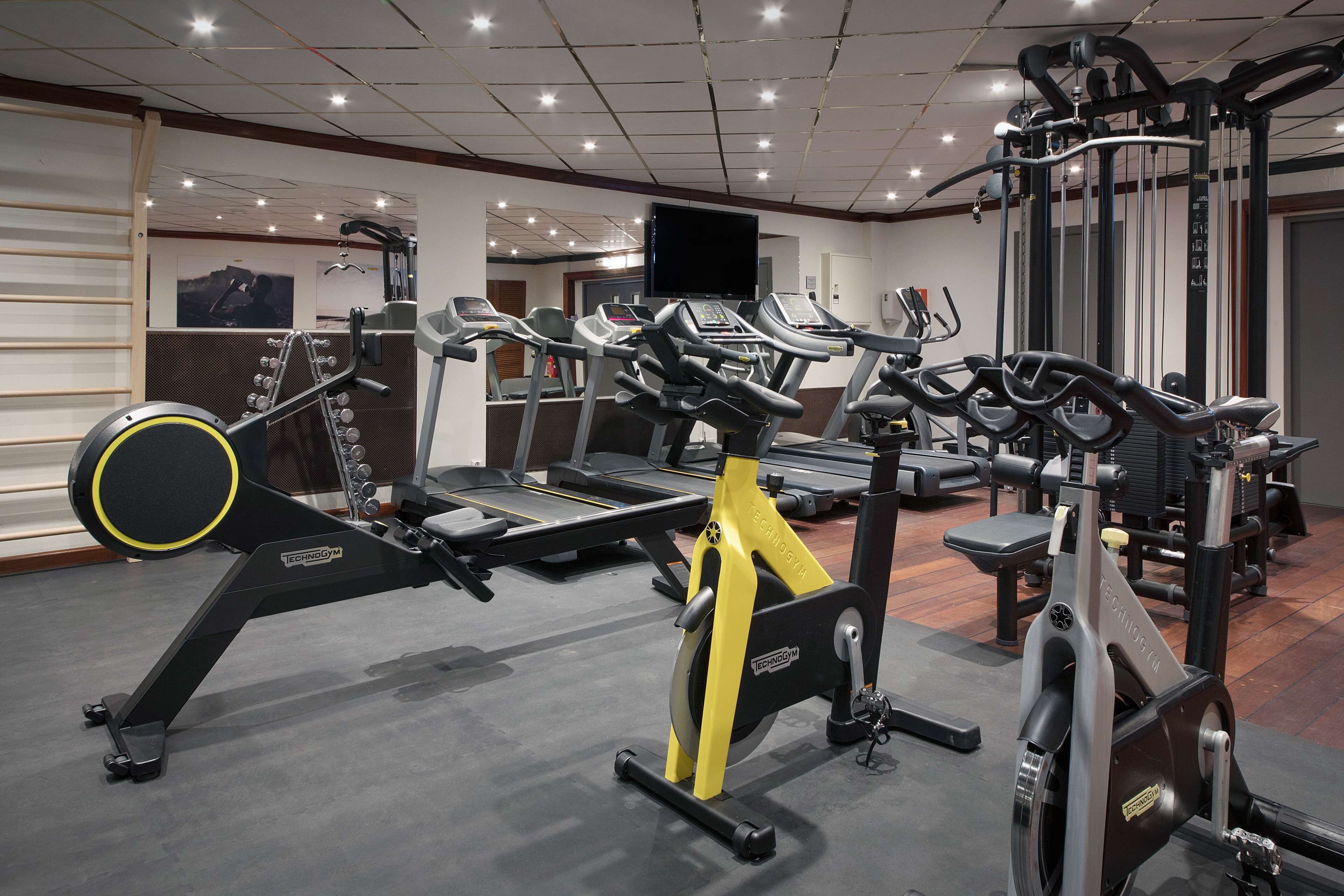 Un gimnasio con diverso equipo de ejercicio, incluyendo cintas de correr y máquinas de pesas.