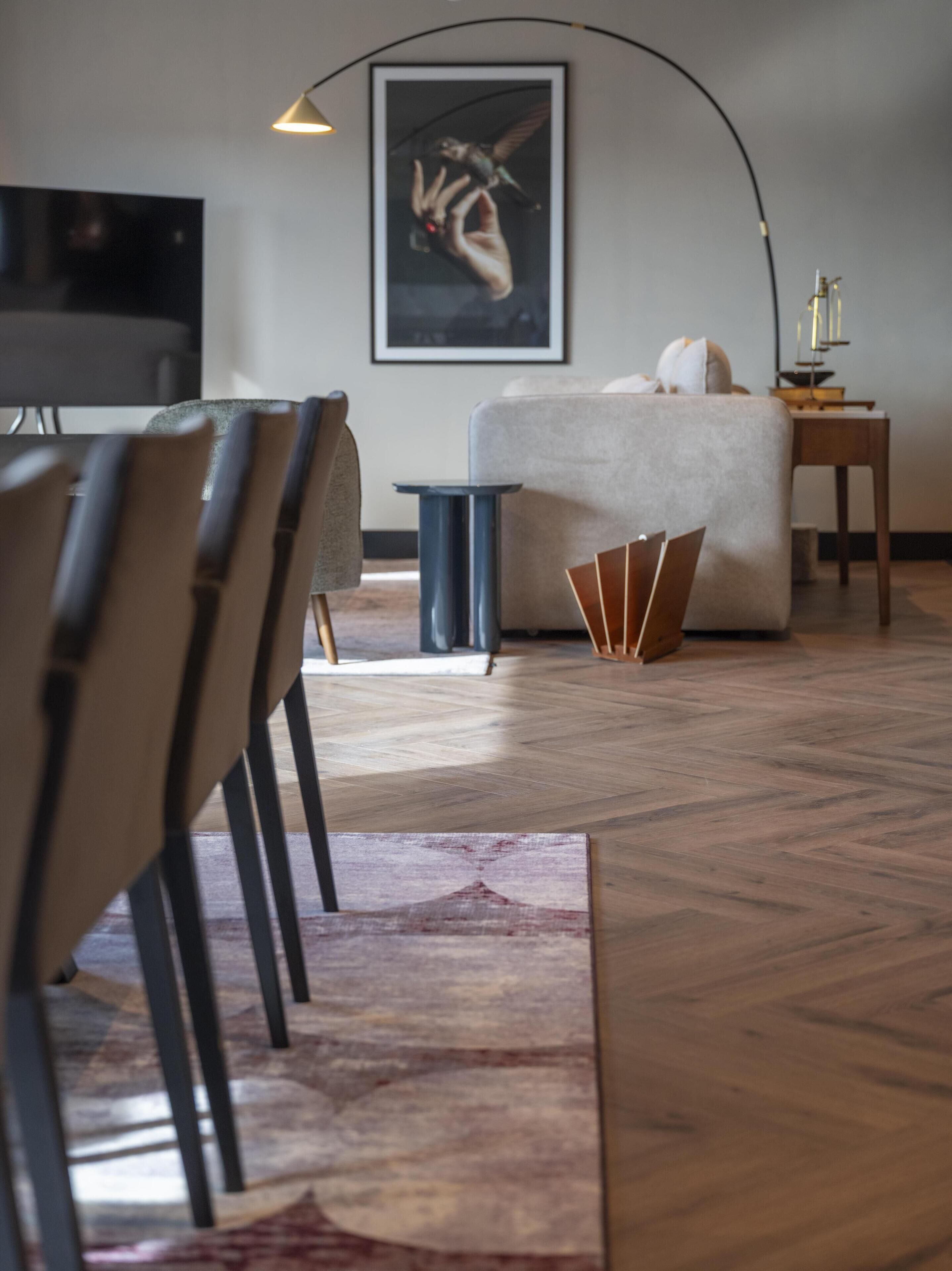 Ein modernes Wohnzimmer mit Sofa, Sesseln, einem Couchtisch, einem Fernseher und einem gerahmten Kunstwerk an der Wand.