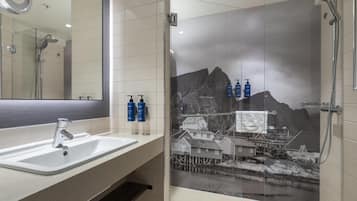 A bathroom with a glass shower enclosure, a sink, and a mirror.