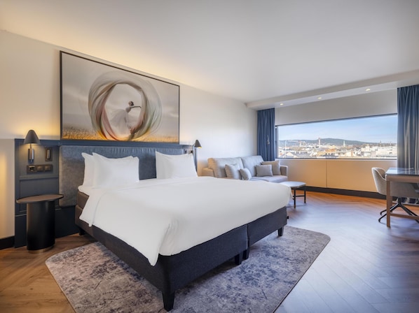 Una habitación de hotel moderna con una cama grande, un escritorio y vistas a la ciudad.