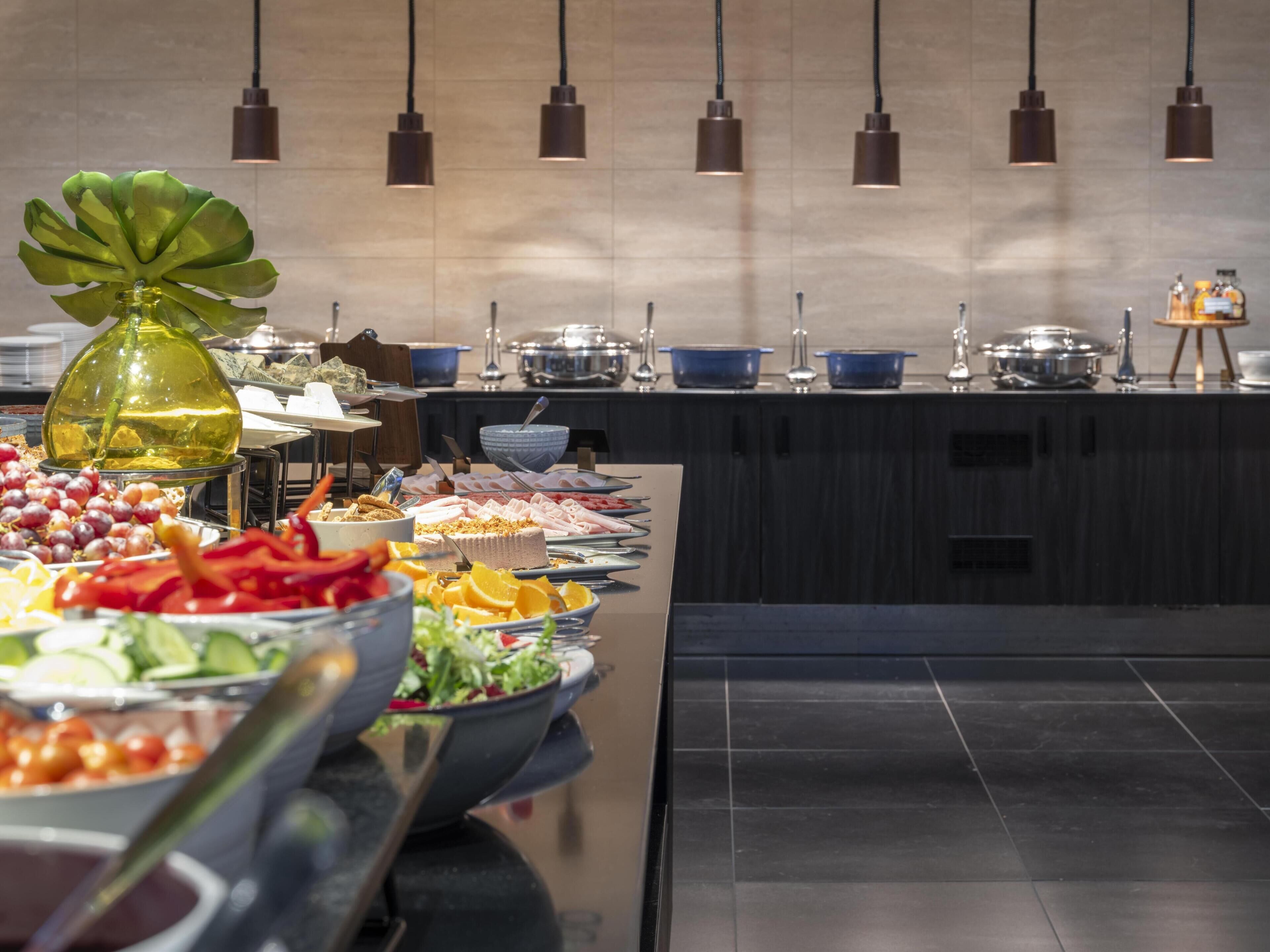 A buffet setup with various food items and a decorative plant.