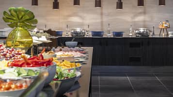 A buffet setup with various food items and a decorative plant.