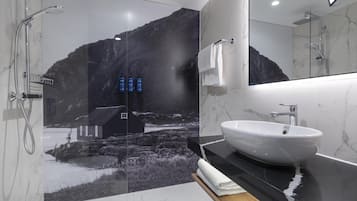 A modern bathroom with a large mirror, a white sink, and a shower.