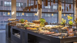 Un bufé con diferentes opciones de comida y una decoración moderna con luces colgantes y paredes de ladrillo.