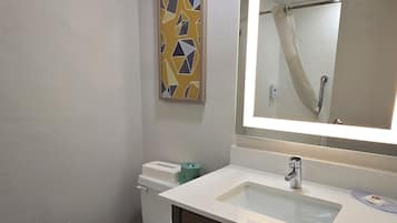 A bathroom with a toilet, sink, mirror, and towels.