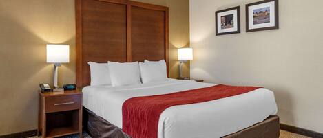 A hotel room with a large bed, two bedside lamps, a nightstand, and two framed pictures on the wall.