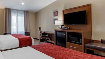 Ein Hotelzimmer mit zwei Betten, einem Schreibtisch mit Stuhl, einem Fernseher, einer Mikrowelle und einem kleinen Kühlschrank.