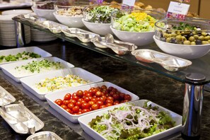 Enjoy a sumptuous spread of international cuisine at our buffet, featuring a variety of dishes served on elegant trays and bowls.