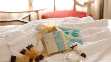 Una cama con una toalla blanca, una bolsa de regalo y artículos de aseo.