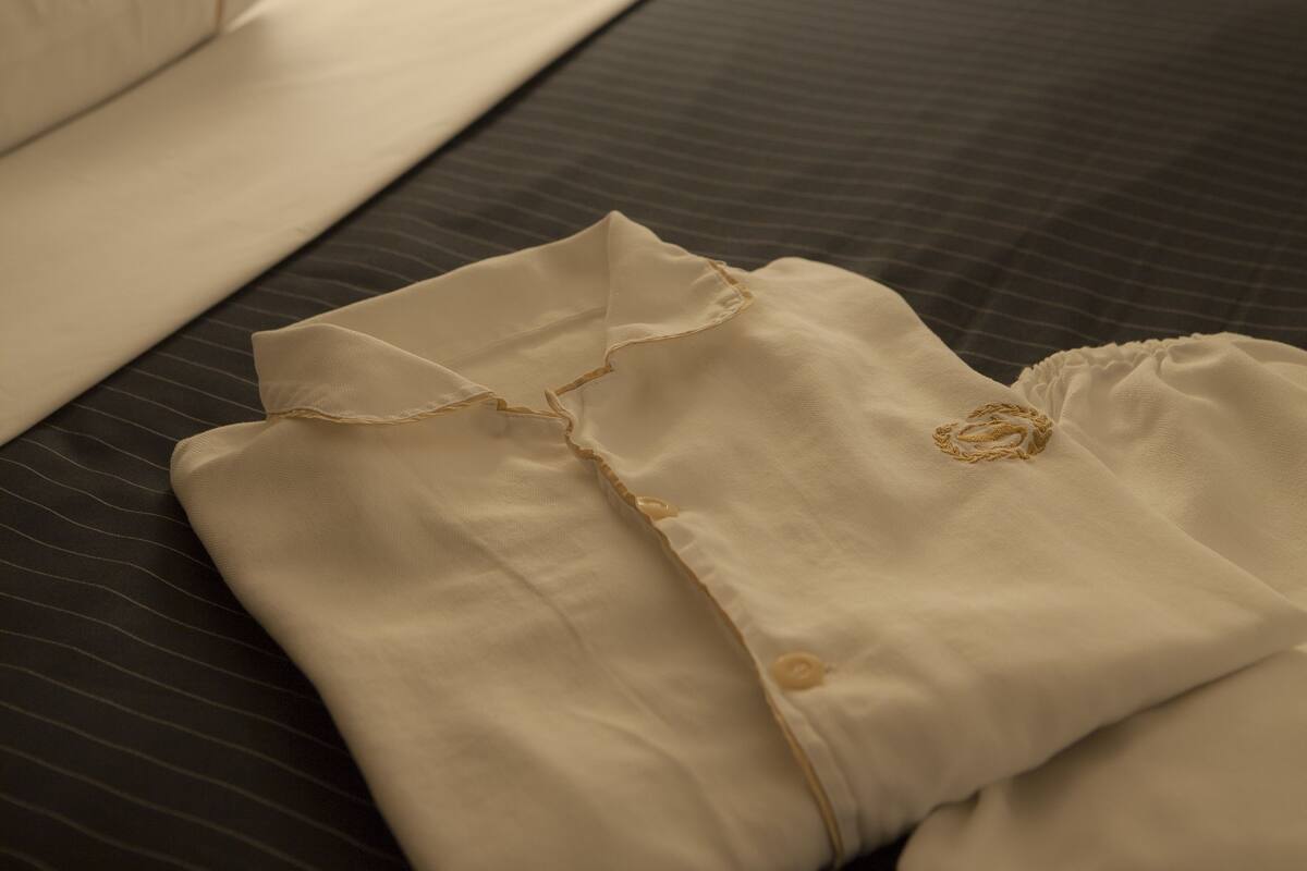 Una cama bien hecha con ropa blanca y una prenda doblada encima.