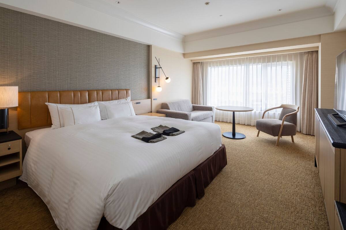 Una habitación de hotel con una cama grande, un escritorio, una silla y un televisor.