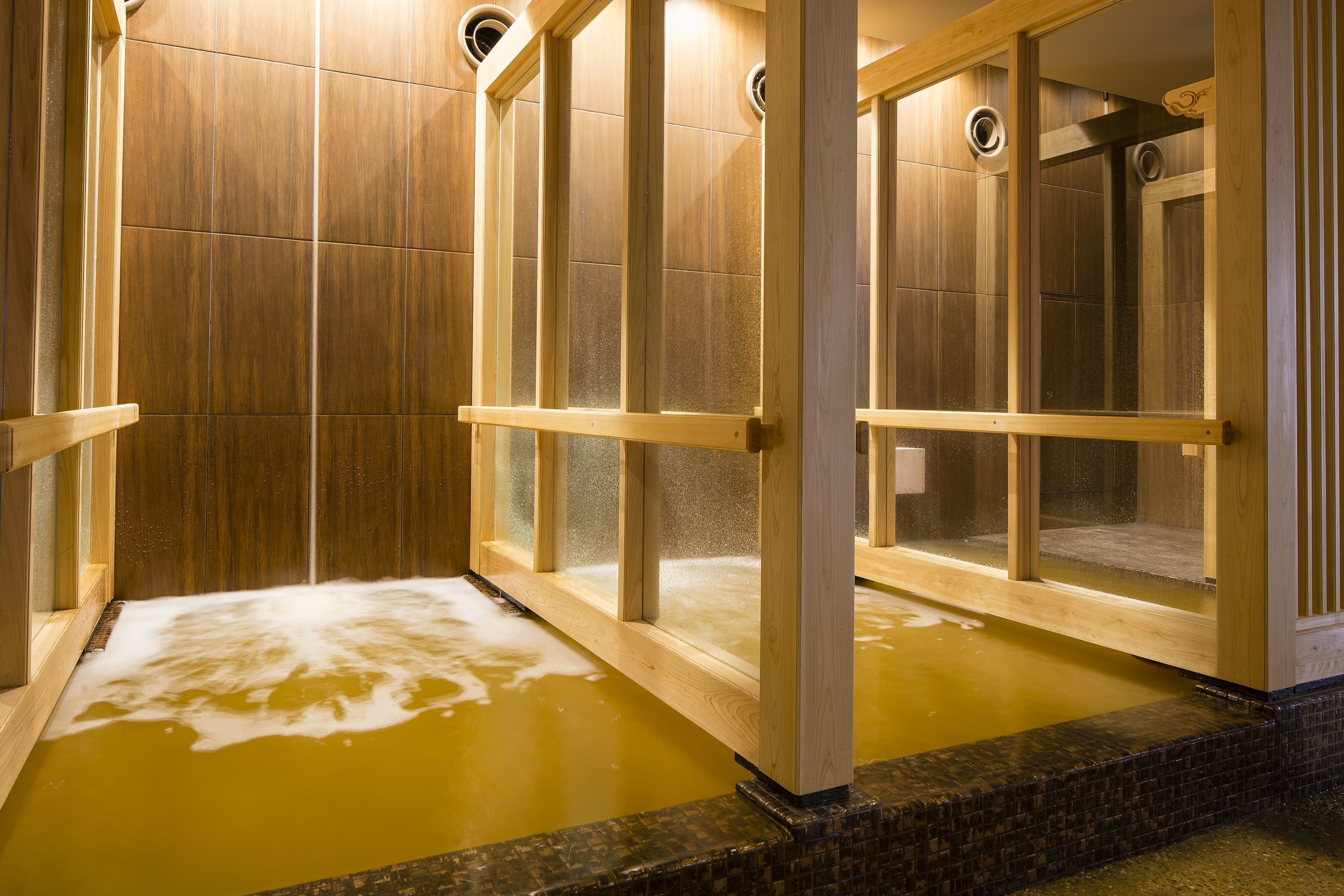 Un onsen japonais traditionnel, avec des portes coulissantes en bois et un intérieur carrelé.