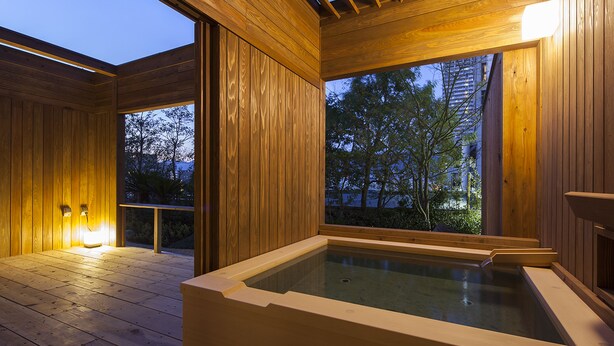 Un spa de madera con un jacuzzi, ventanas amplias y techo de madera.