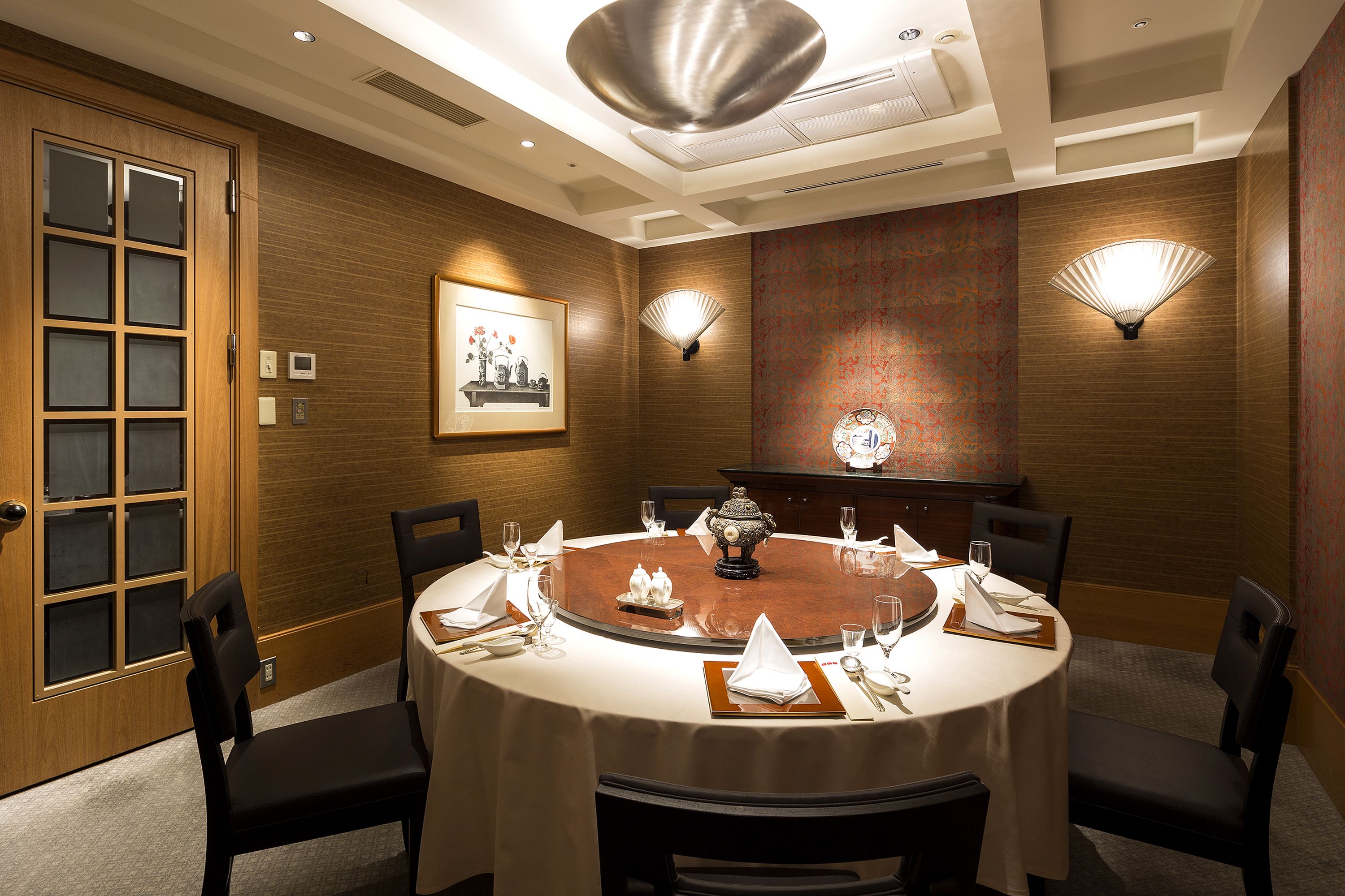 A dining room with a round table, chairs, and a chandelier.