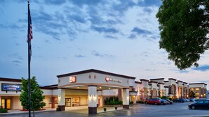 A hotel with a central entrance, a flagpole, and a parking lot.