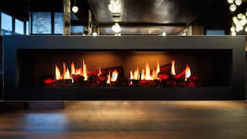 Ein moderner Kamin mit schlichtem, minimalistischem Design, ausgestattet mit einer rechteckigen Feuerstelle und einer eleganten, dunklen Oberfläche.