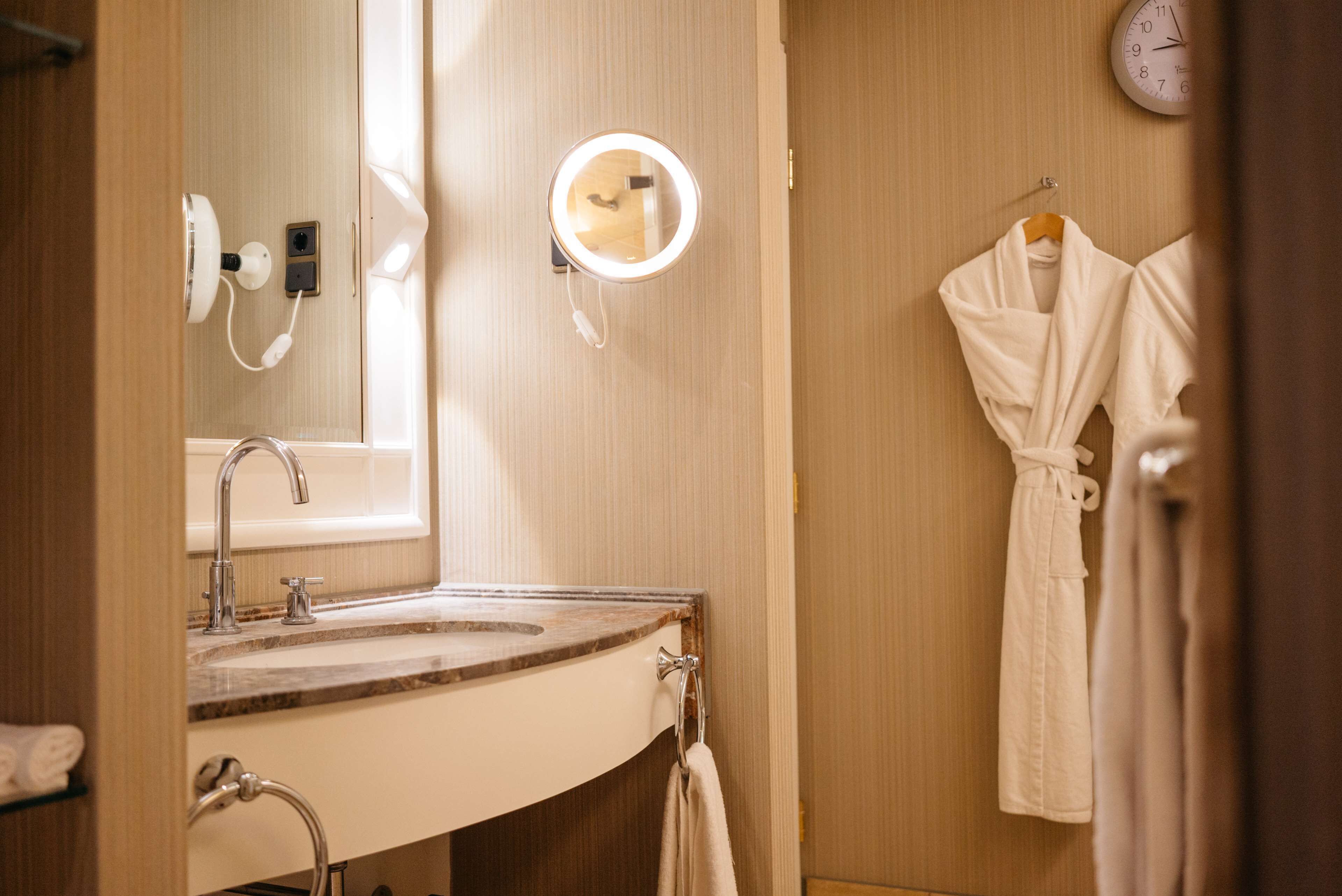 A bathroom with a sink, mirror, and robe hanging on the wall.