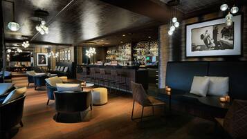A modern bar area with seating, a bar counter, and a television screen.