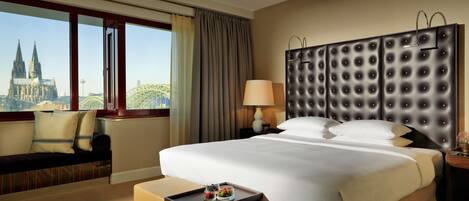Habitación de hotel con una cama grande, vistas a una catedral y al paisaje urbano.