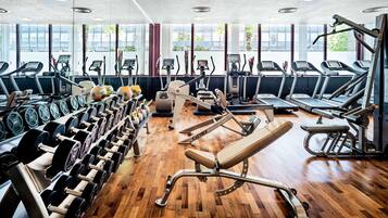 Une salle de sport équipée de tapis de course, de vélos elliptiques et de bancs de musculation.