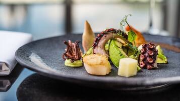 A plate of food with octopus, scallops, and greens.
