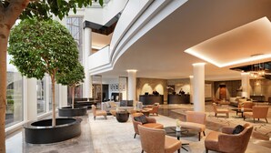 Eine geräumige Lobby mit Empfangstresen, Sitzbereichen und einem großen Baum.
