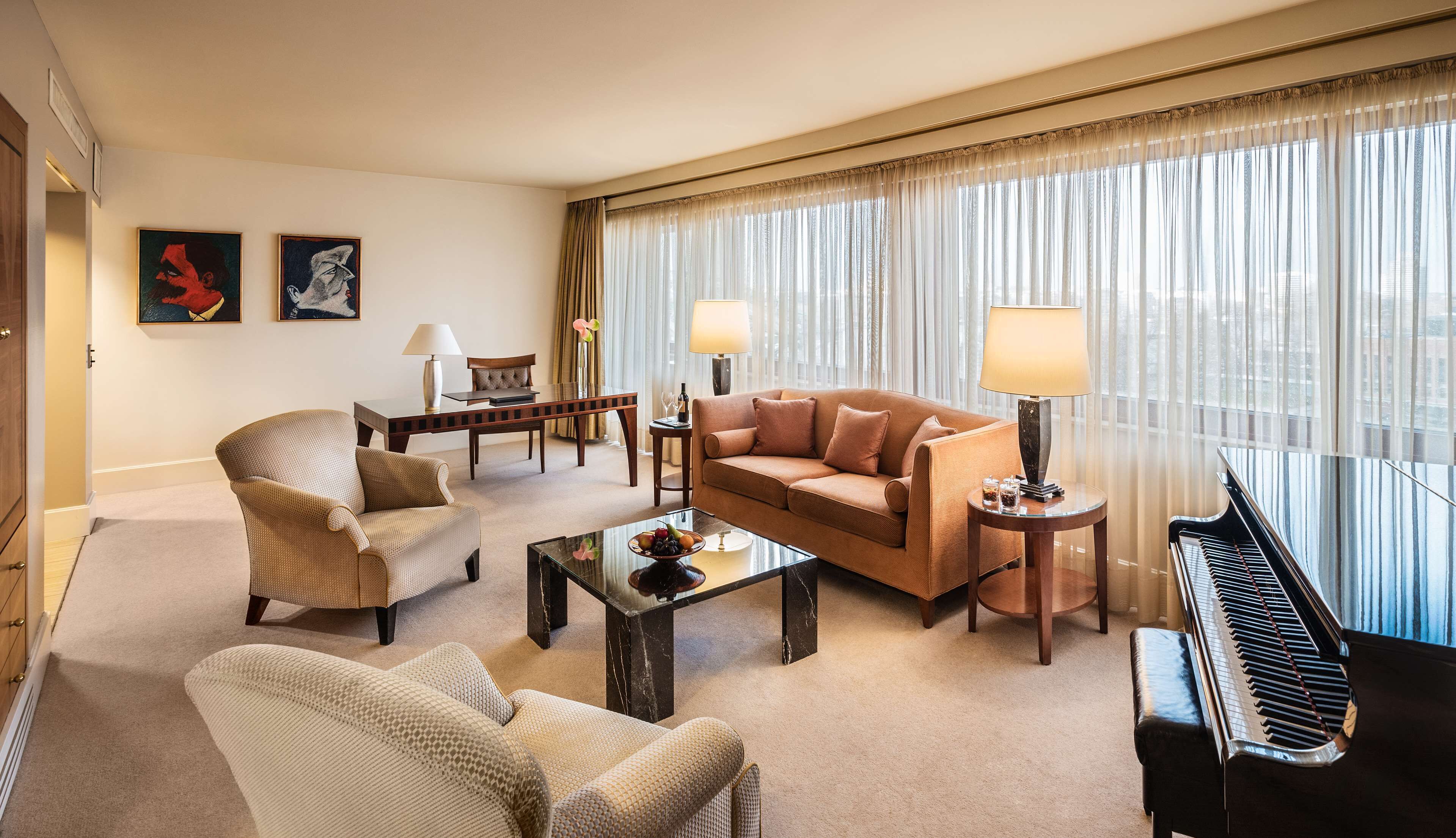 A well-lit living room with a sofa, armchair, coffee table, and a piano.