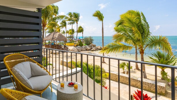 A balcony with wicker chairs, a small table with drinks, and a view of the beach and ocean. - Three Waters Resort and Marina, Islamorada, a Tribute Portfolio Resort (Islamorada)