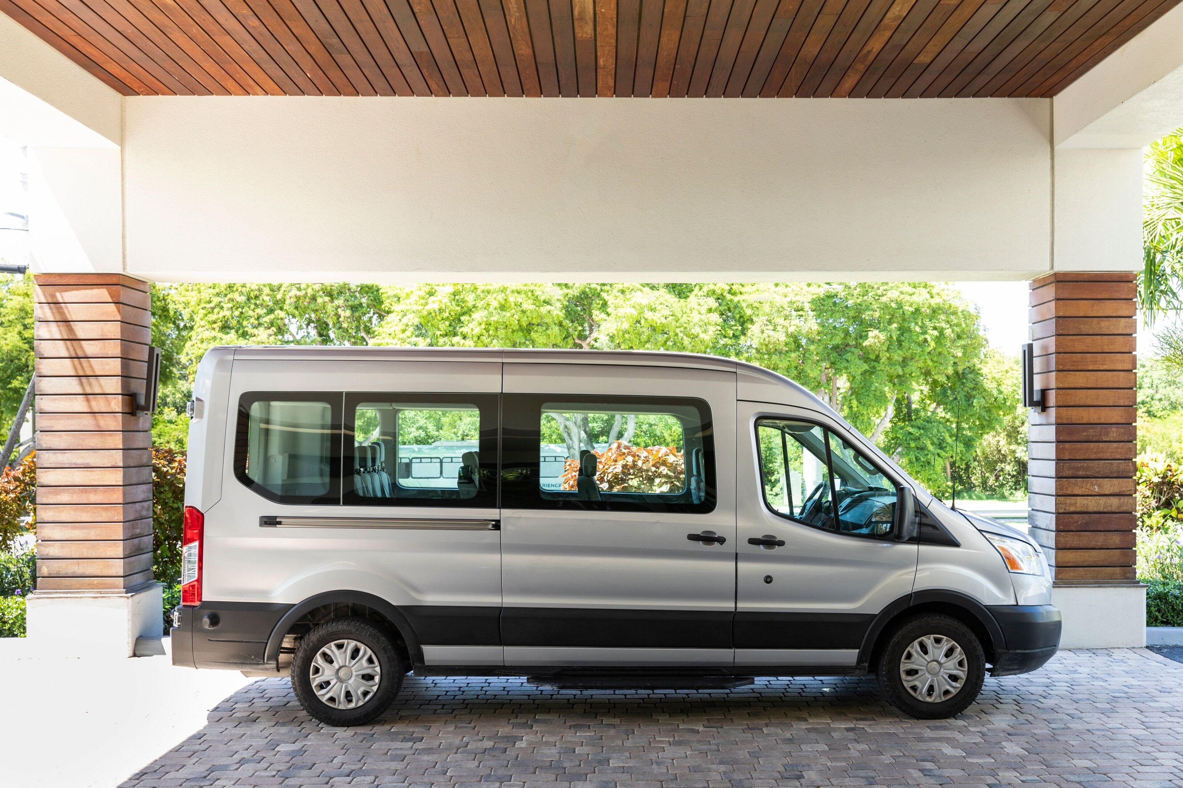 A white van parked under a covered area with a brick floor.