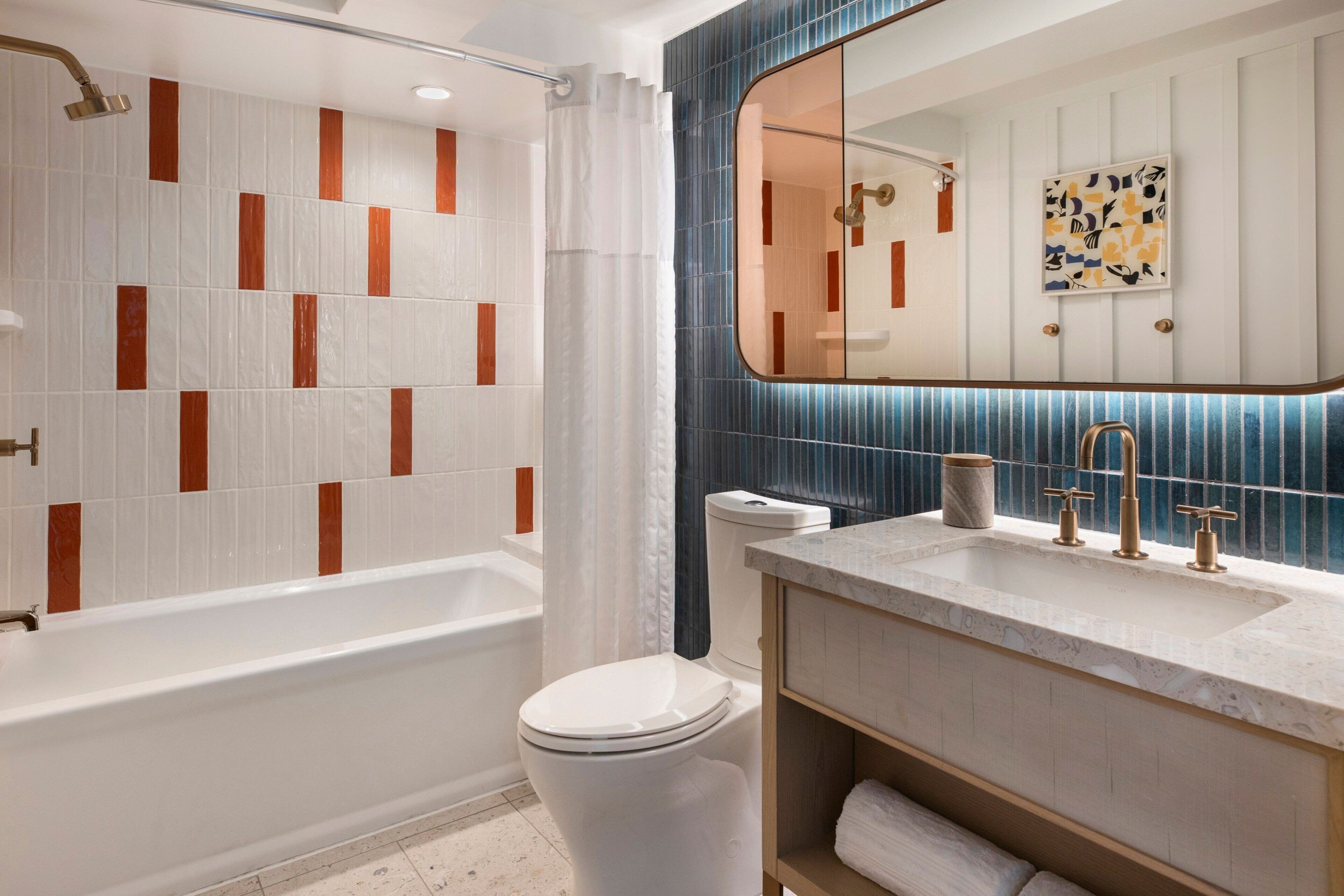 A modern bathroom with a bathtub, toilet, and vanity with a sink.