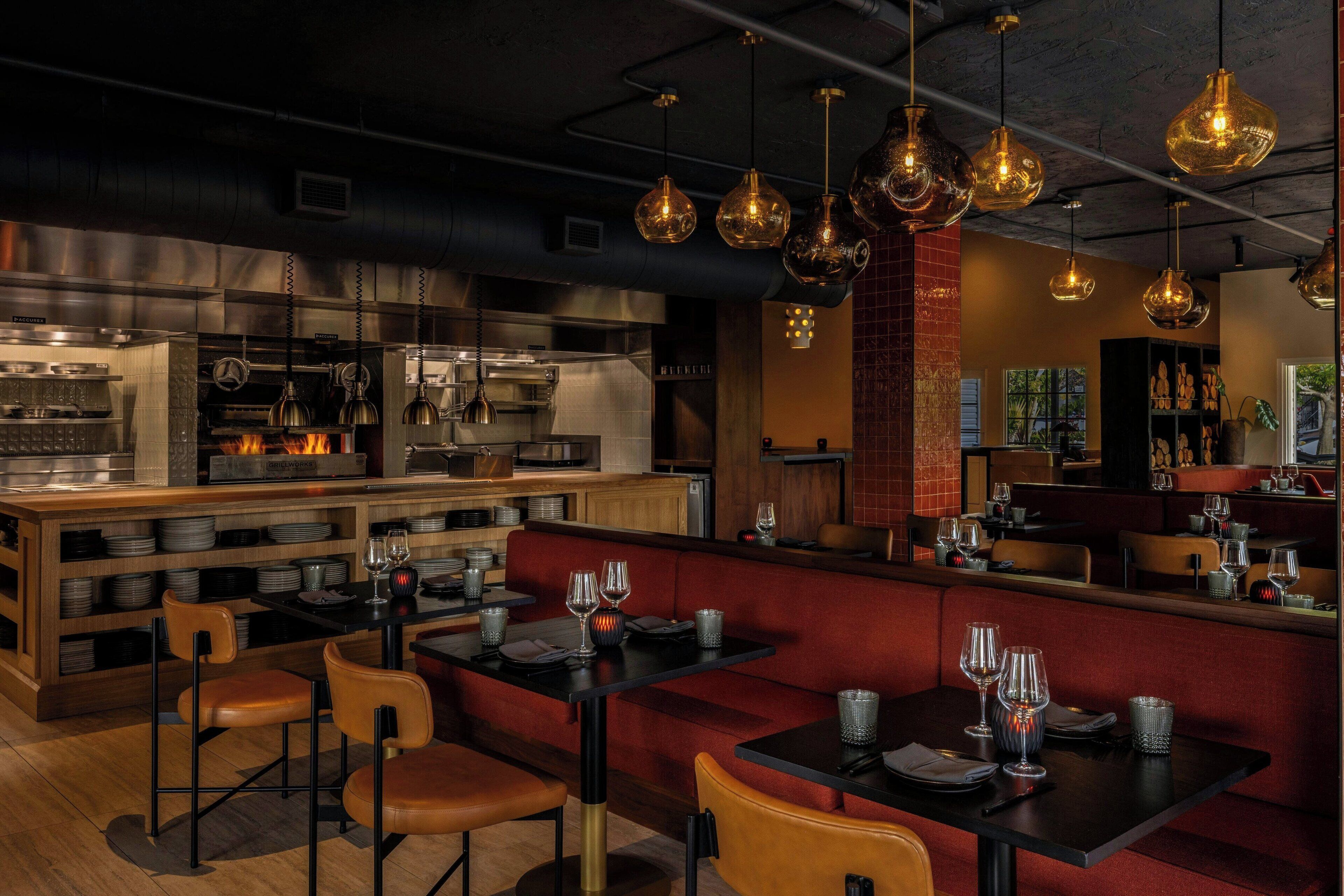 A restaurant with a bar area, booths, and a kitchen in the background.