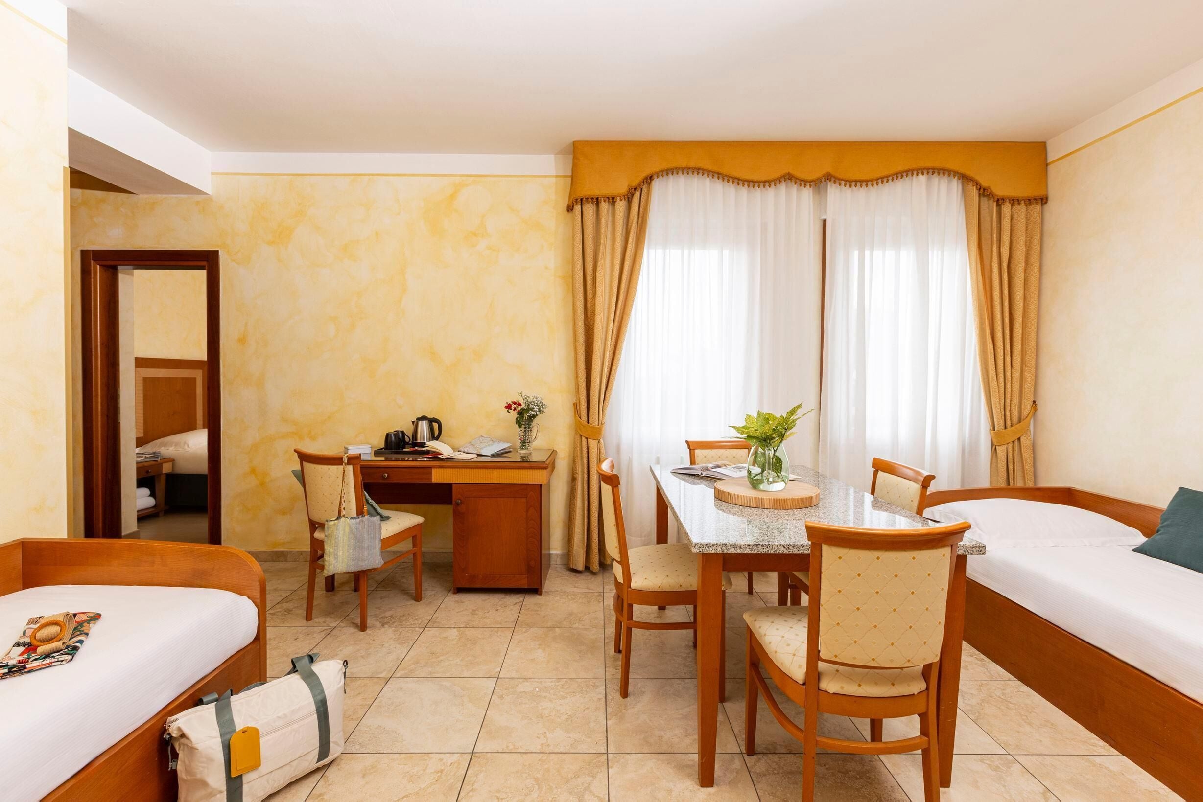 A hotel room with a bed, a desk, a dining table, and chairs.