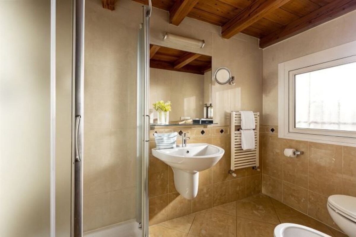 A bathroom with a glass shower enclosure, a sink, and a toilet.