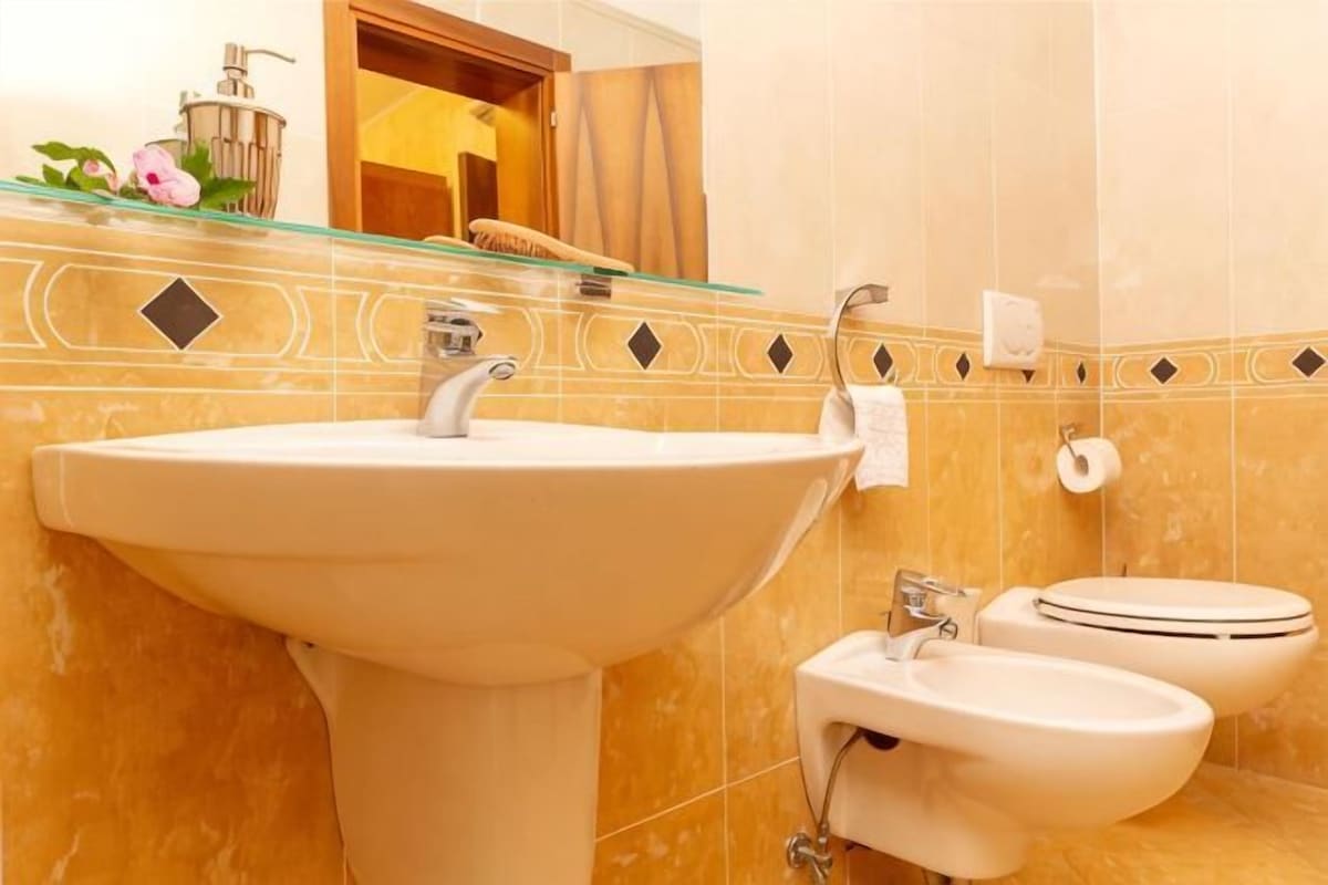 A bathroom with a sink, bidet, and toilet.