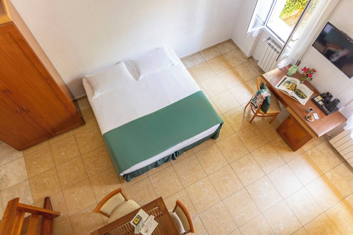 A room with a bed, a desk, a chair, and a television.