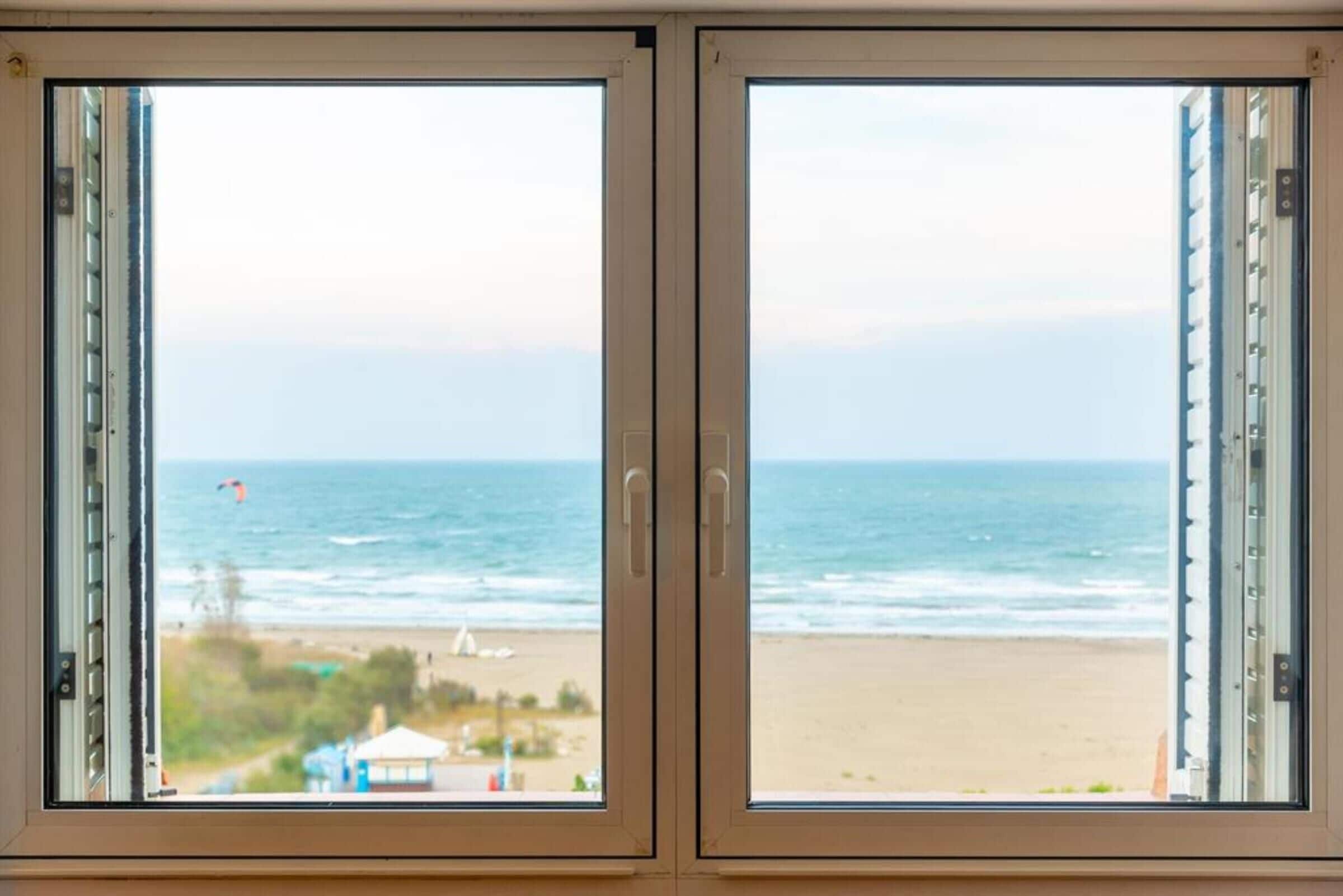 Una finestra con vista sulla spiaggia e sull'oceano.