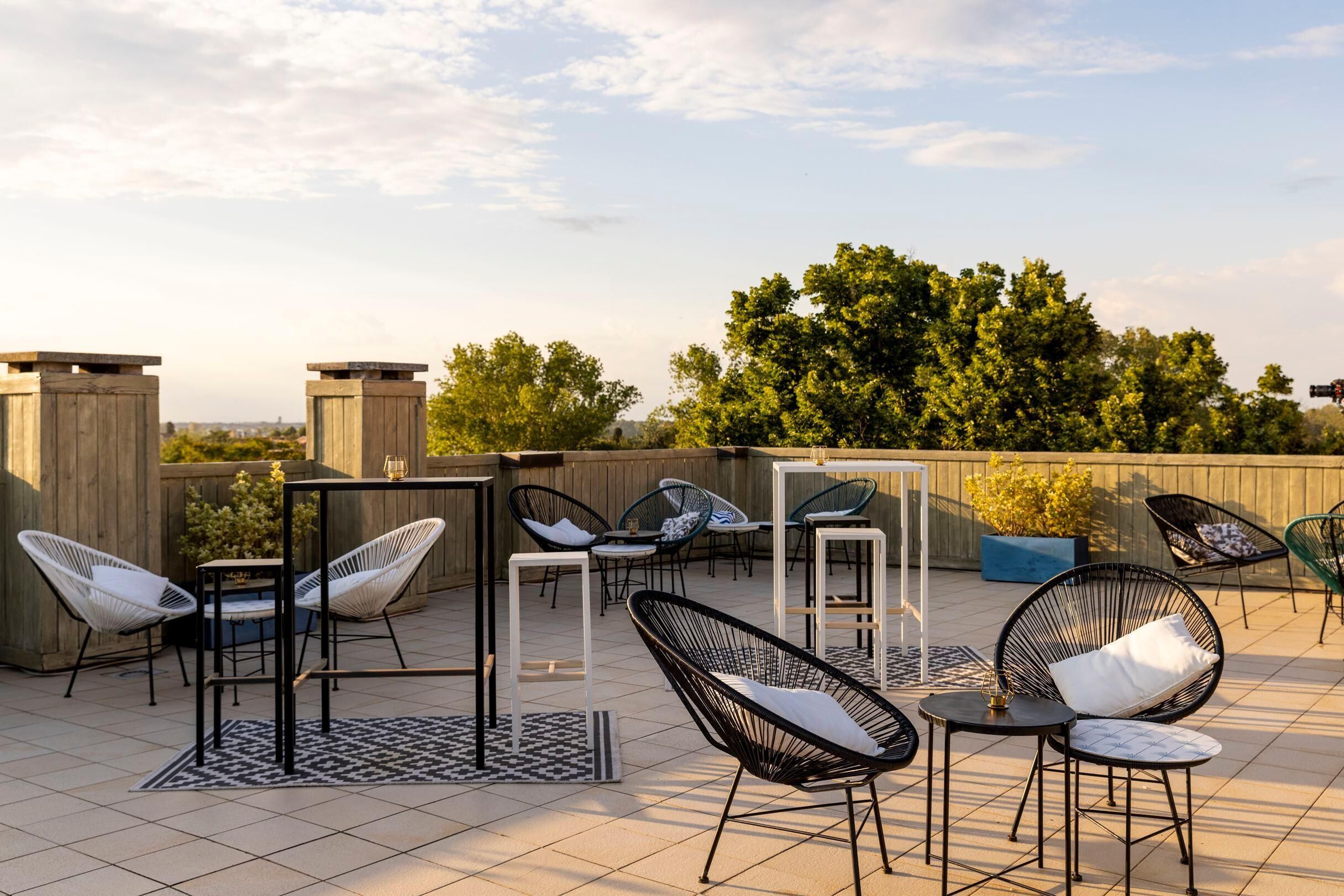 An outdoor patio with seating, tables, and a view of trees.