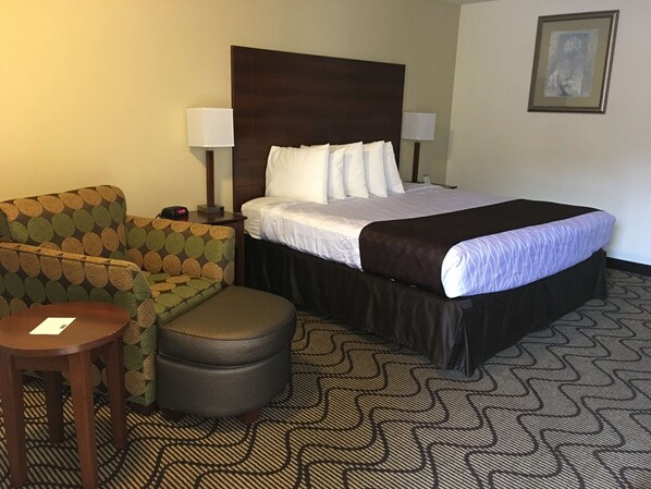 A hotel room with a bed, a sofa, a small table, and a nightstand.